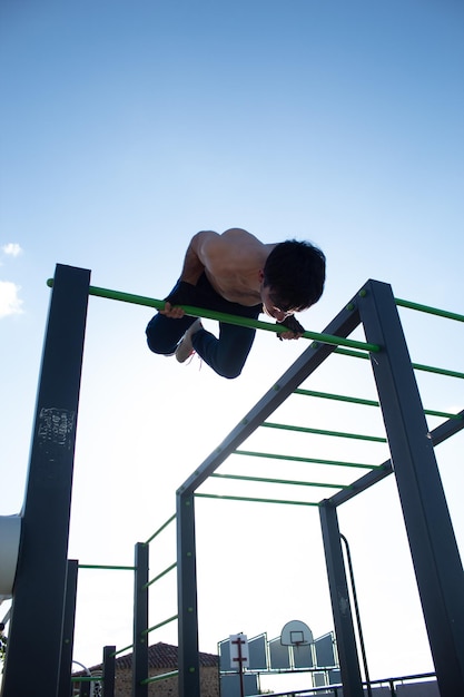 Atletische jonge man doet skin the cat-oefening tijdens geavanceerde training