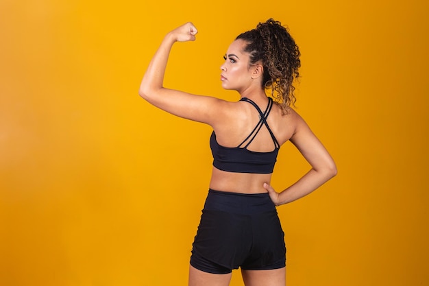 Atletische jonge vrouw die rugspieren en biceps toont