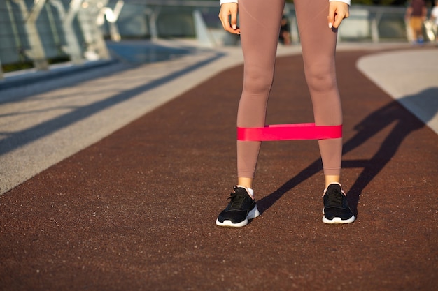 Atletische jonge vrouw die 's ochtends traint met fitnessgom op de brug. Vrije ruimte voor tekst