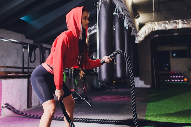 Atletische jonge vrouw die sommige oefeningen met een kabel doet openlucht.