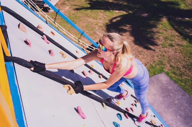 Atletische jonge vrouw die traint en touwen beklimt in het trainingskamp voor touwen