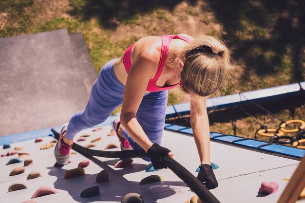 Atletische jonge vrouw die traint en touwen beklimt in het trainingskamp voor touwen