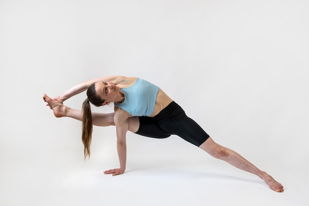 Atletische jonge vrouw traint yoga pilates stretching oefening geïsoleerd