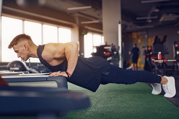 Atletische jongeman doet push-ups in de sportschool