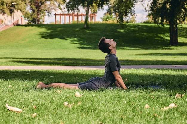 Atletische jongeman in sportkleding doet yoga in het park