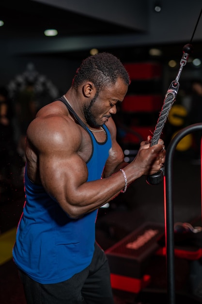 Atletische knappe bodybuilder in sportschool Sterke gespierde donkere man die zijn lichaam traint