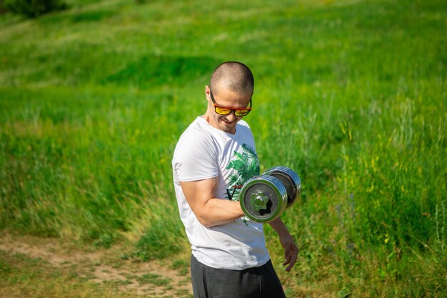 Atletische man doet biceps-oefeningen met halter. Man in wit t-shirt doet buitentraining