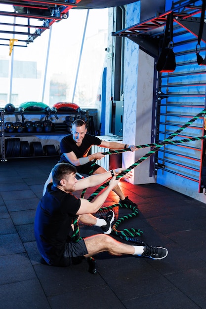 Atletische man doet oefeningen met de hulp van zijn persoonlijke trainer in een openbare sportschool.