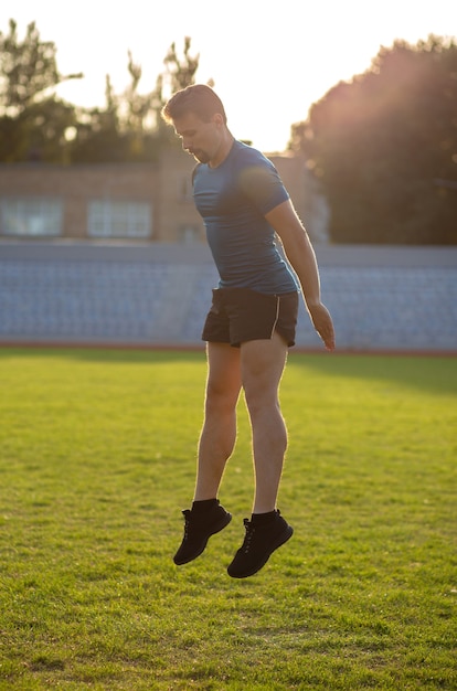 Atletische man draagt blauw t-shirt en zwarte korte broek die in het stadion springt