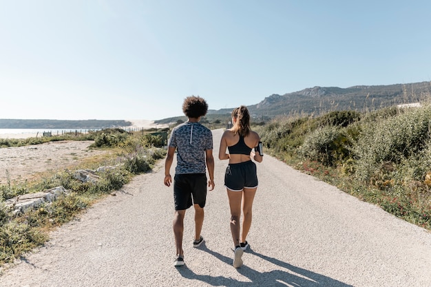 Atletische man en vrouw die langs weg lopen