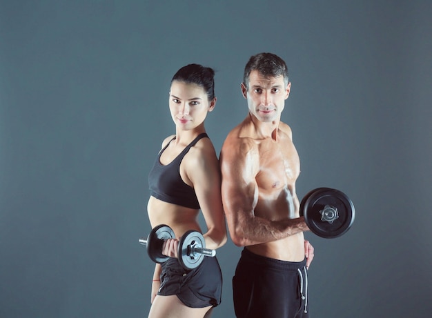 Atletische man en vrouw met dumbells Persoonlijke fitnessinstructeur Persoonlijke training