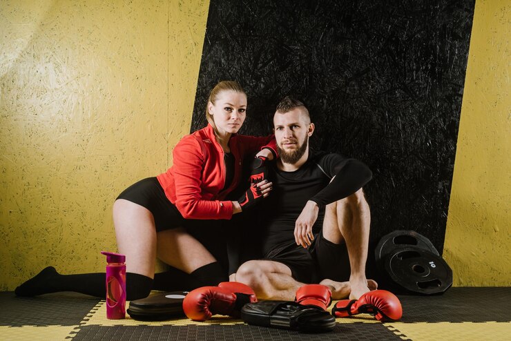 Atletische man en vrouw rusten na trainingen in de sportschool met bokspersoneel