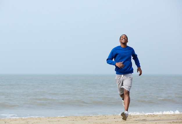 Atletische man genieten van een joggen op het strand