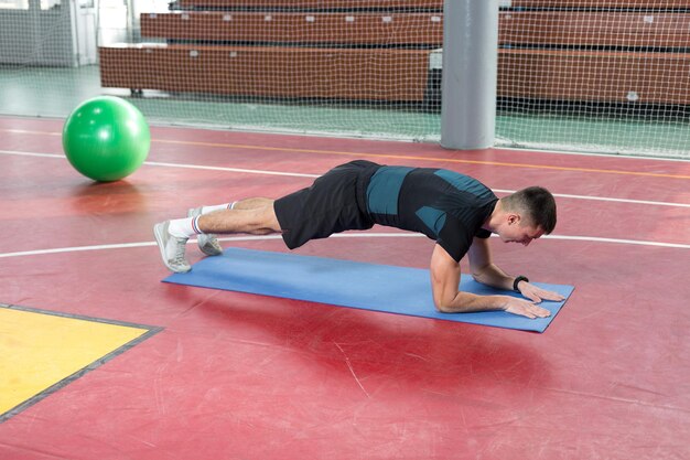 Foto atletische man in sportkleding en fitness-tracker die oefeningen doet in de sportschool.