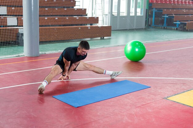 Atletische man in sportkleding en fitnesstracker die oefeningen doet in de sportschool.