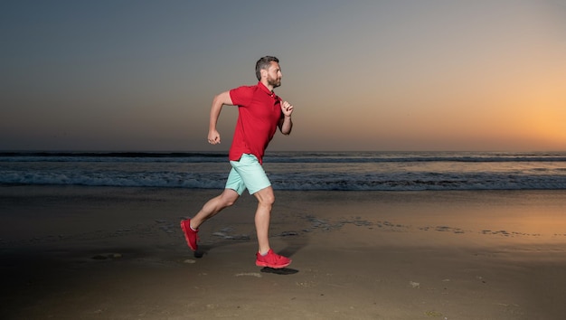 Atletische man loper draait op zonsondergang zomer strand uithoudingsvermogen