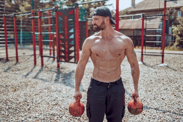 Atletische man uit te werken met een kettlebell op straat gym gym werf.