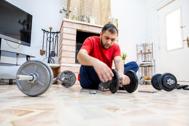 Atletische man voegt meer gewichten toe aan de dumbell