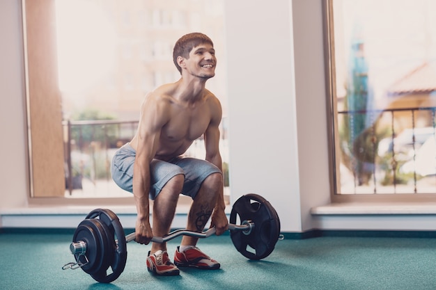 Atletische man voert training barbell op te heffen