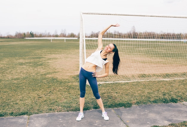 Atletische meisje doet oefening warming-up in het stadion