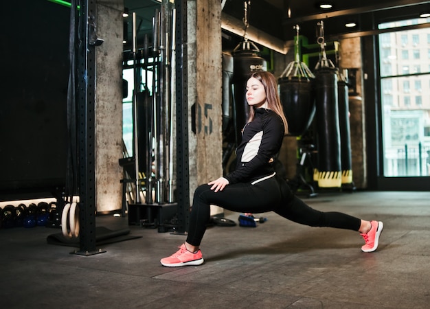 Atletische meisje strekt haar benen voor training in de sportschool