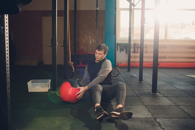 Atletische mens die buikoefening op de vloer doet. Mens die training doen die een geneeskundebal gebruiken bij de gymnastiek.