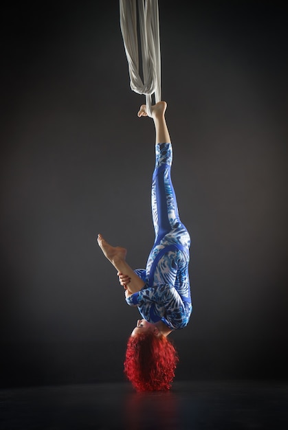 Foto atletische sexy luchtcircusartiest met roodharige in blauw kostuum die trucs maakt op de luchtzijde.