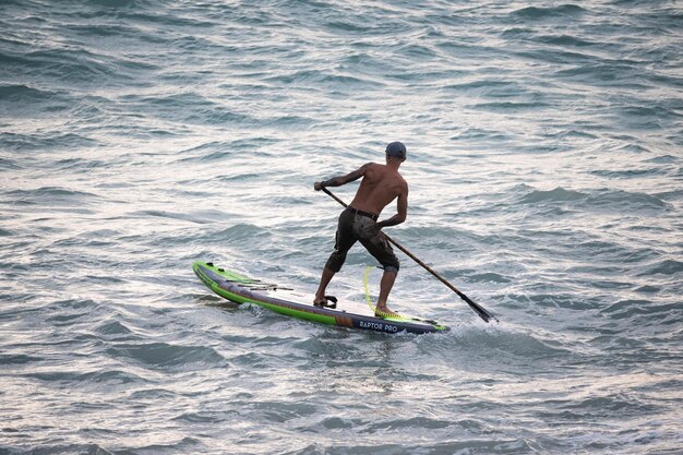 Foto atletische surfer zwemt met een paddle op een supboard in de zee stand up paddleboarding