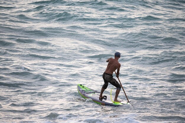 Foto atletische surfer zwemt met een paddle op een supboard in de zee stand up paddleboarding