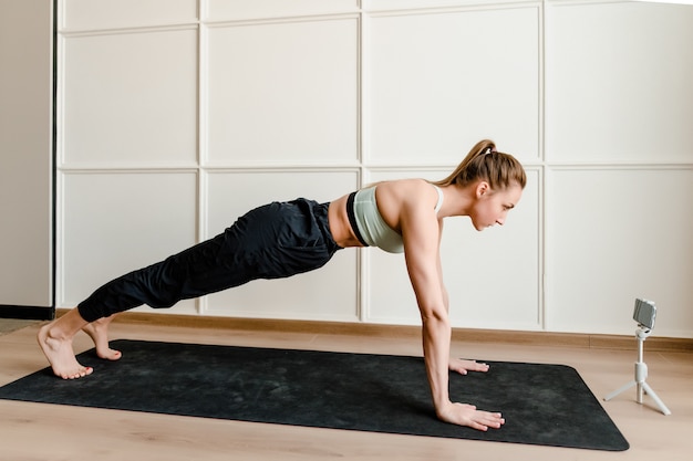 Atletische vrouw die lichaamsbeweging thuis op yogamat doen