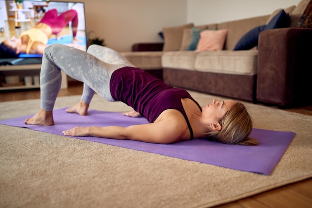 Atletische vrouw doet glute bridge-oefening tijdens thuistraining