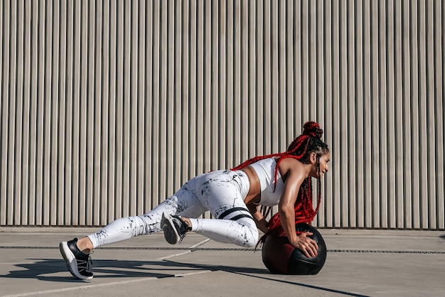 Atletische vrouw doet oefening draaien met med bal Kracht en motivatie Foto van sportieve vrouw in modieuze sportkleding