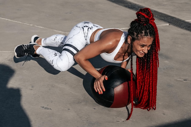 Atletische vrouw doet oefening draaien met med bal Kracht en motivatie Foto van sportieve vrouw in modieuze sportkleding