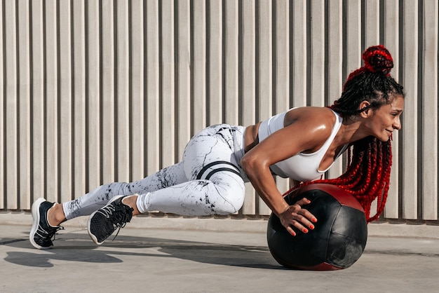 Atletische vrouw doet oefening draaien met med bal Kracht en motivatie Foto van sportieve vrouw in modieuze sportkleding