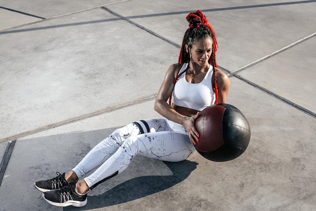 Foto atletische vrouw doet oefening met med bal kracht en motivatie foto van sportieve vrouw in modieuze sportkleding