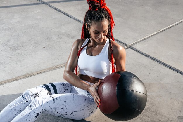 Atletische vrouw doet oefening met med bal Kracht en motivatie Foto van sportieve vrouw in modieuze sportkleding