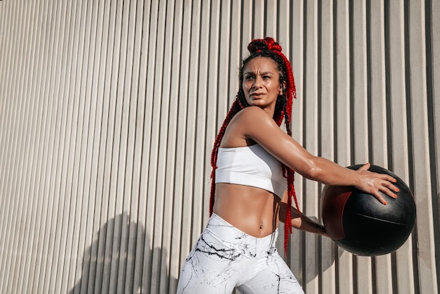 Atletische vrouw doet oefening romp draait met med bal. Kracht en motivatie. Foto van sportieve vrouw in modieuze sportkleding