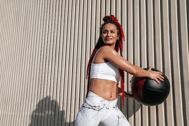 Foto atletische vrouw doet oefening torso draait met med bal kracht en motivatie foto van sportieve vrouw in modieuze sportkleding