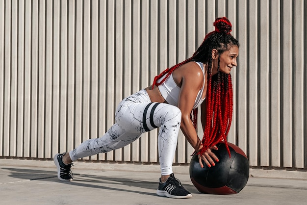 Atletische vrouw doet oefening wissel van benen met med bal Kracht en motivatie Foto van sportieve vrouw in modieuze sportkleding