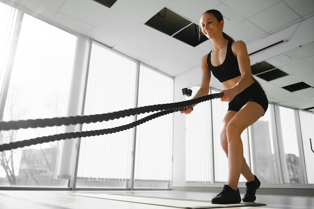 Atletische vrouw in een sportschool oefent met gevechtstouwen tijdens haar fitnesstraining Intervaltraining met hoge intensiteit Ze is gespierd en bezweet