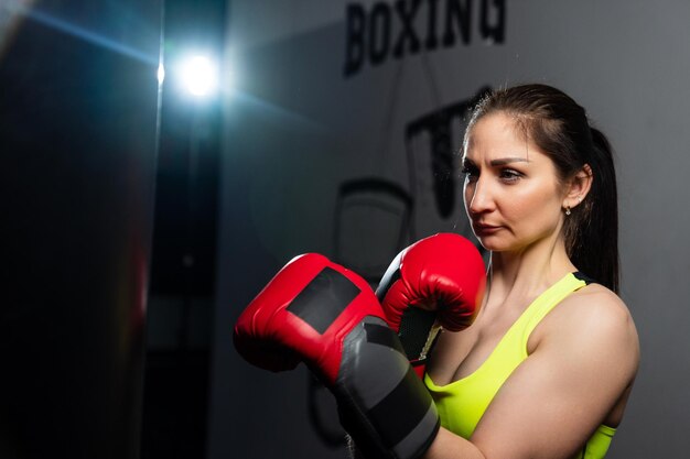 Foto atletische vrouw in een trainingspak die stoten oefent op een bokszak