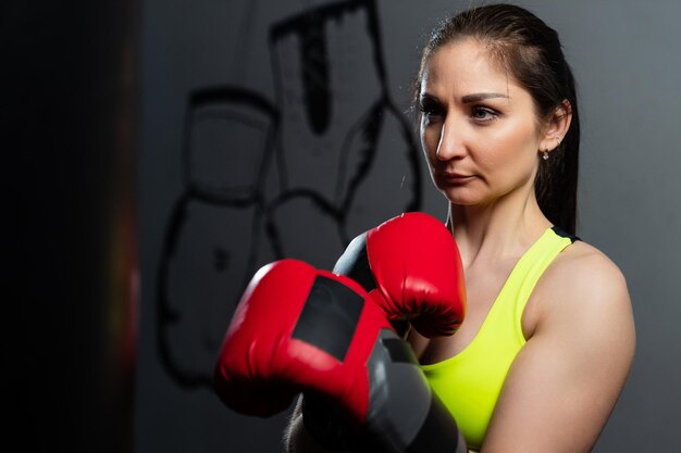 Atletische vrouw in een trainingspak die stoten oefent op een bokszak