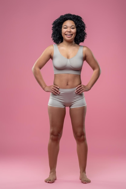 Atletische vrouw in lingerie op een roze achtergrond