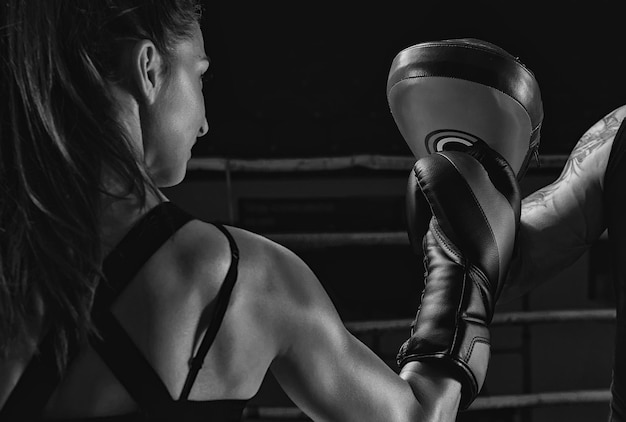 Atletische vrouw in rode korte broek en top is aan het boksen met een trainer Boksen en mixed martial arts concept