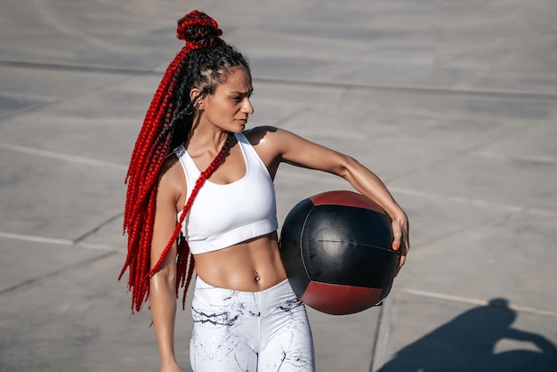 Atletische vrouw met med bal Kracht en motivatie Foto van sportieve vrouw in modieuze sportkleding