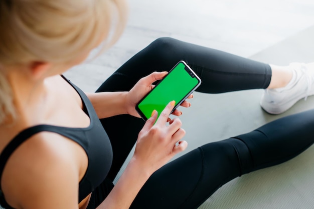 Foto atletische vrouw met smartphone in fitness studio close-up