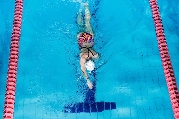 Atletische vrouw zwemmen met hoed en bril zwemmen in zwembad