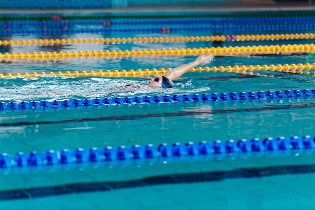 Atletische vrouw zwemmen met hoed en bril zwemmen in zwembad