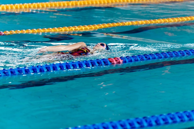 Atletische vrouw zwemmen met hoed en bril zwemmen in zwembad
