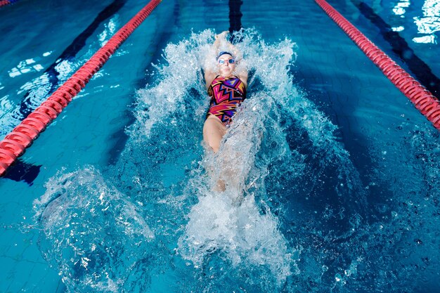 Atletische vrouw zwemmen op de rug met in zwembad